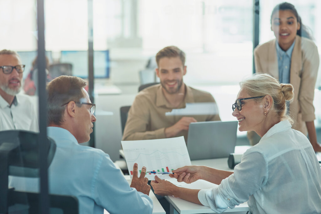 An inspiring business leader guides her diverse executive team through a collaborative performance review and strategic data analysis during a workplace meeting.