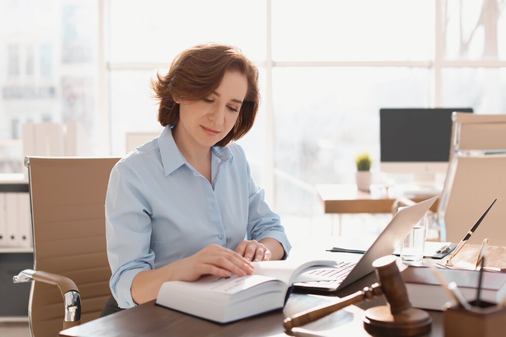 A dedicated legal student or professional reviews case law precedents and statutory regulations during research at her office workstation.