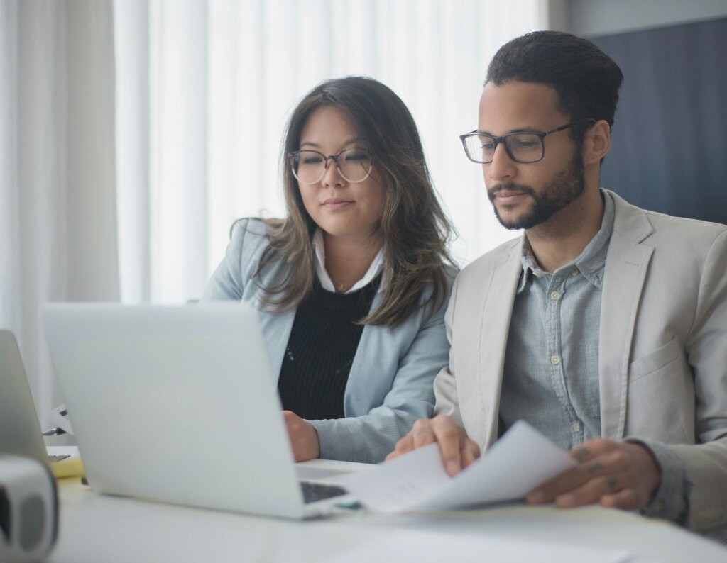 An employer and her trainee review a training plan and logged progress metrics to track completion of course competencies.