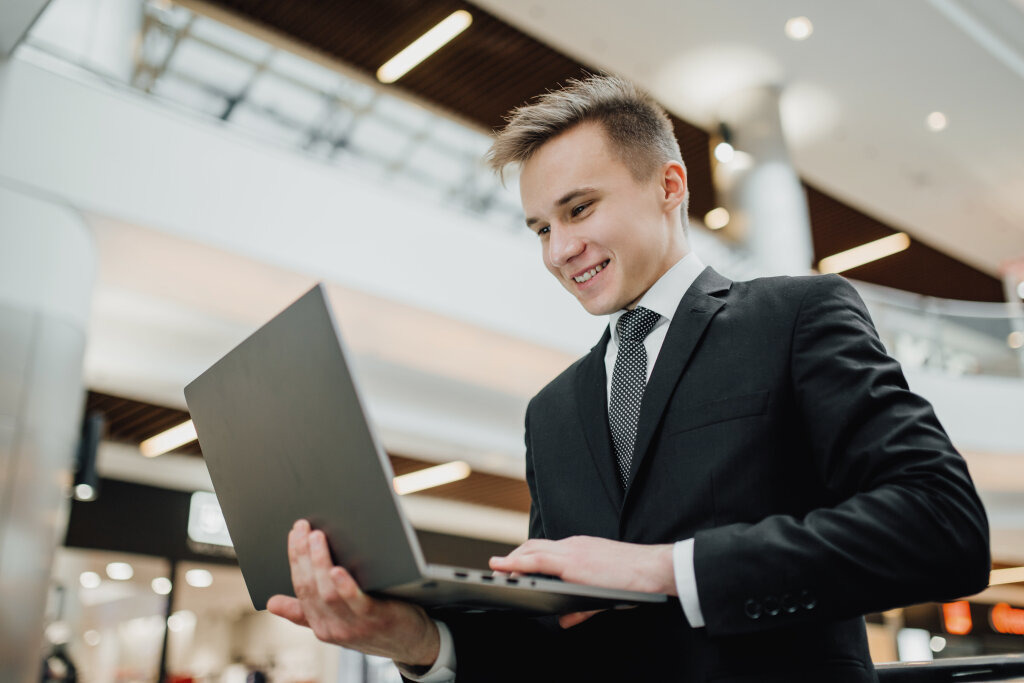 A young trainee in a professional suit works on a laptop, demonstrating practical business administration skills on site.
