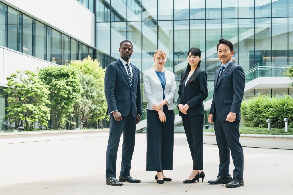 A diverse group of government workers stand together outside a modern government building, ready for their career induction.