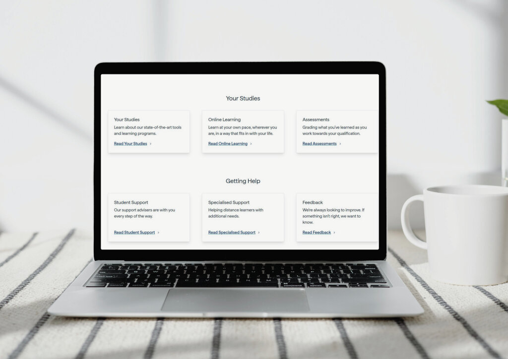 An open laptop sits on a table next to a white mug, displaying a webpage with options for studies, online learning, and student support.