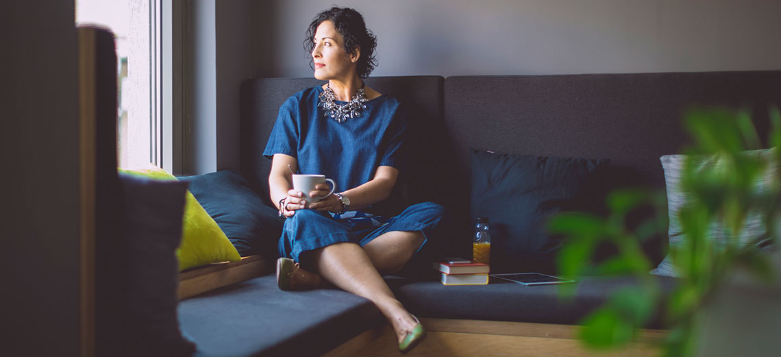 A woman sitting on a sofa while looking out of the window