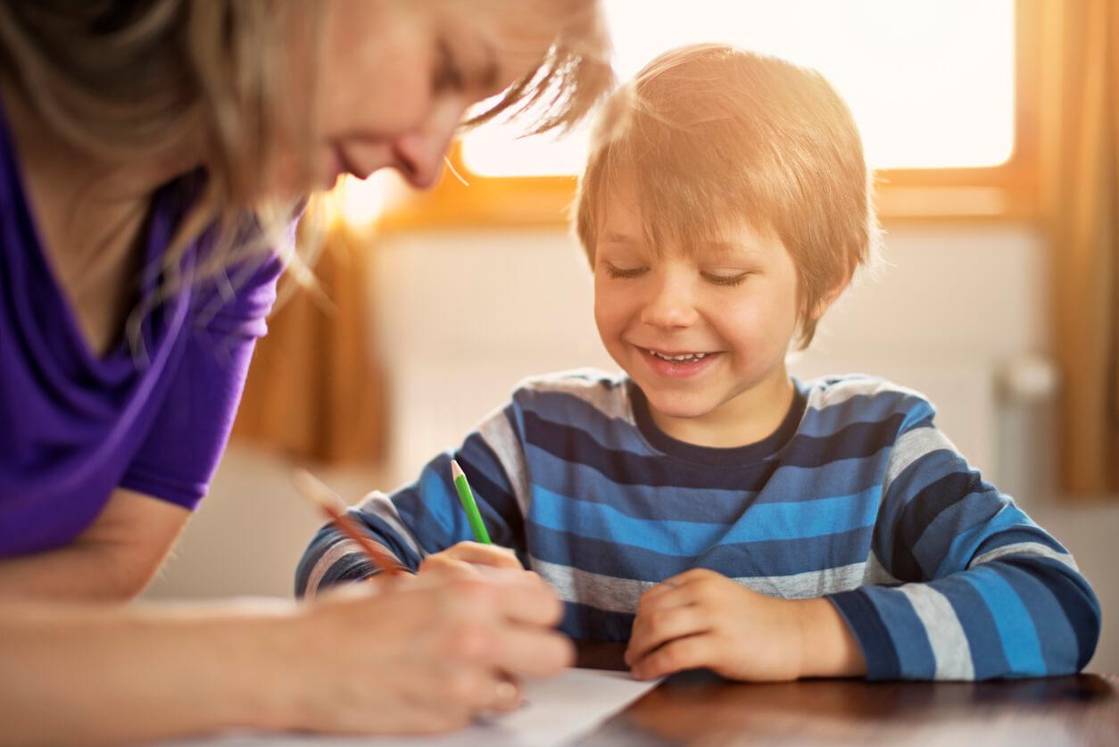Young boy drawing at table with parent