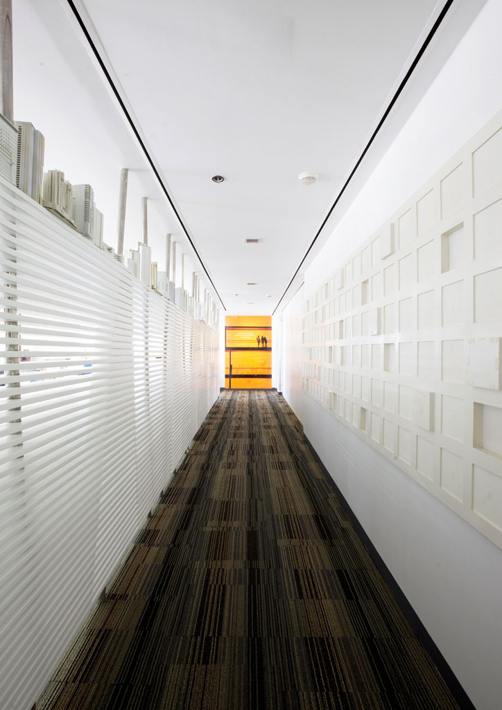 The main hallway from the reception area leading towards Tolentino's office. To the left are interior baffles that dampen noise and provide enough space for light to seep through the hallway. This also provides privacy to the administrative part of the office.
