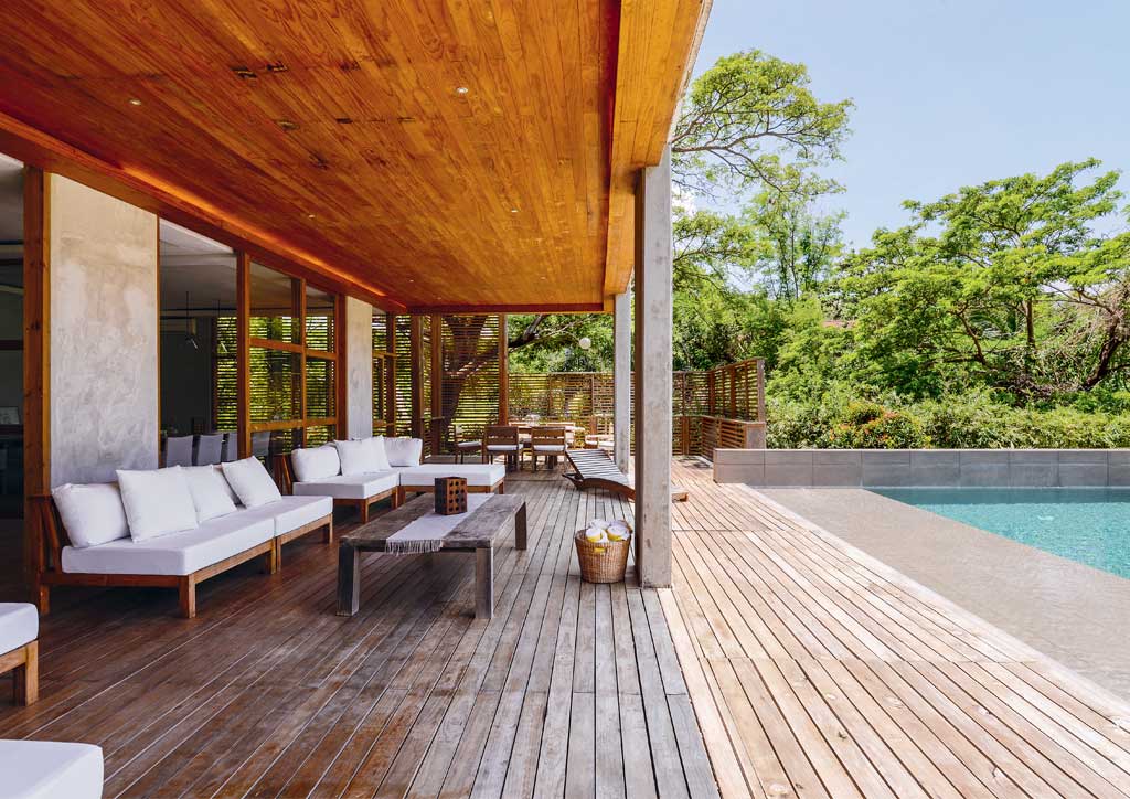 The beach house primarily uses raw materials like palacino wood, and exposed, sealed, and polished concrete to convey a warm aesthetic. 