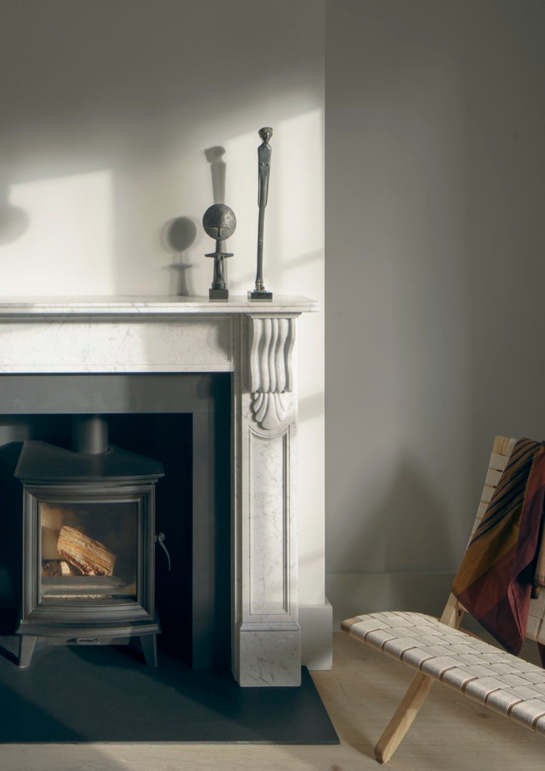a metal furnace inside a marble fireplace next to a leather woven chair