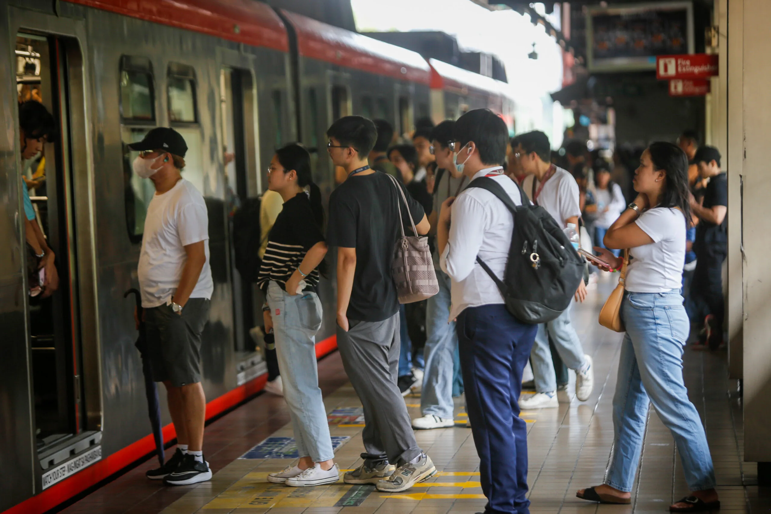 Filipinos lining up to enter a train car at an LRT-1 station.