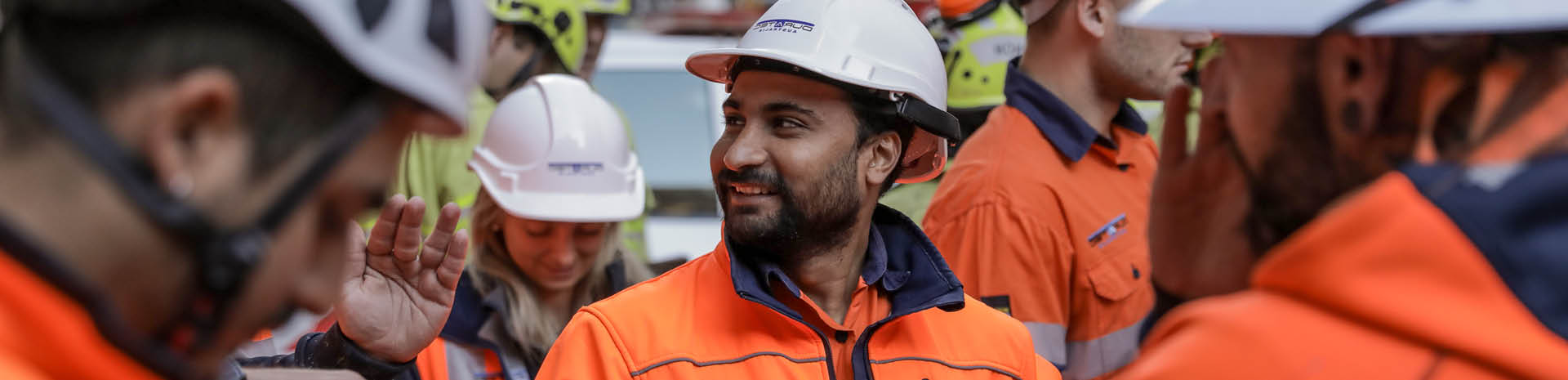 Our people man in hard hat and orange jacket smiling