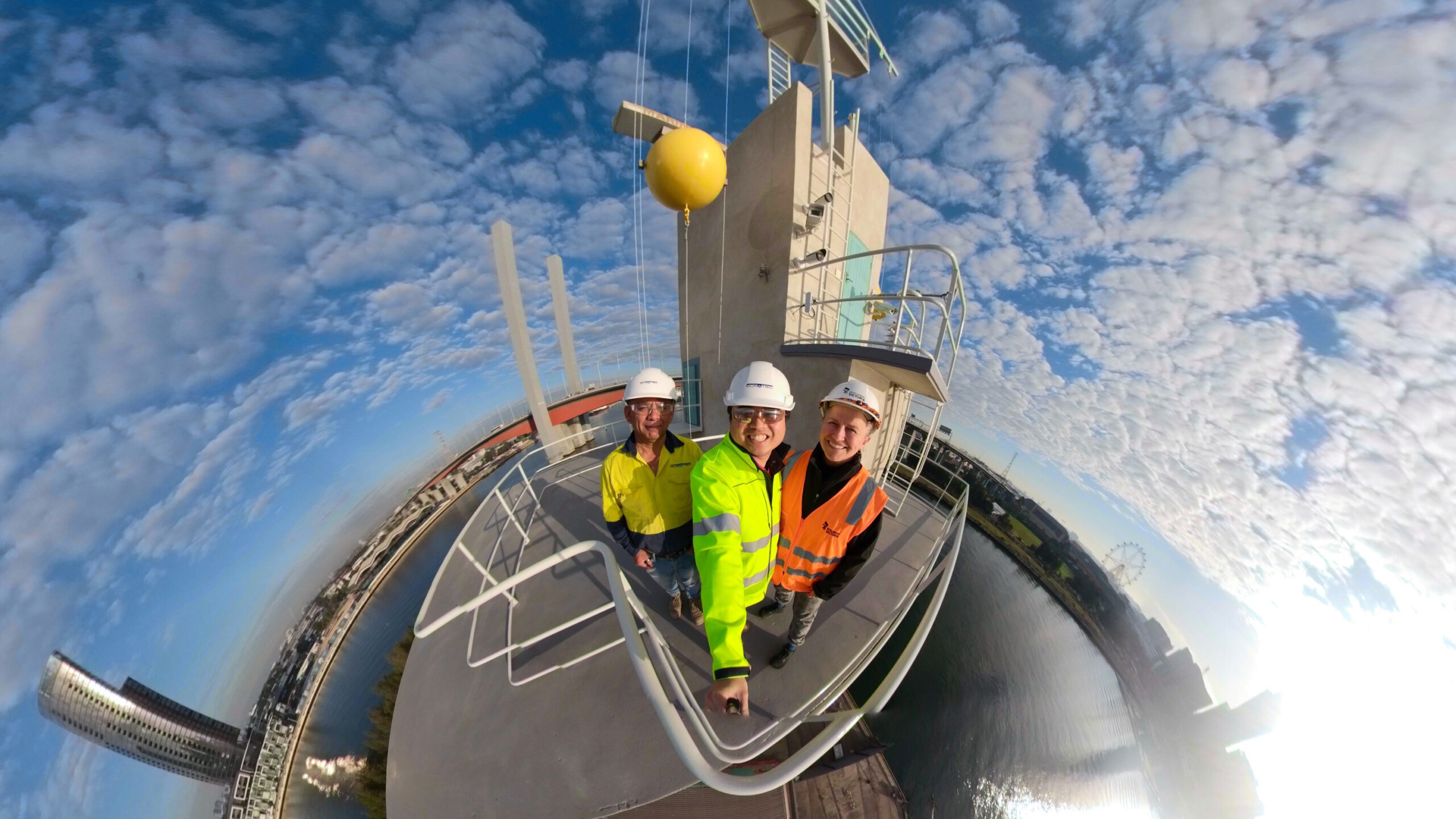 Project team take selfie at the top of North Wharf Shipping Control Tower with Docklands in background.