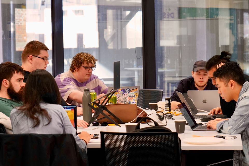 Group working around a table of laptops