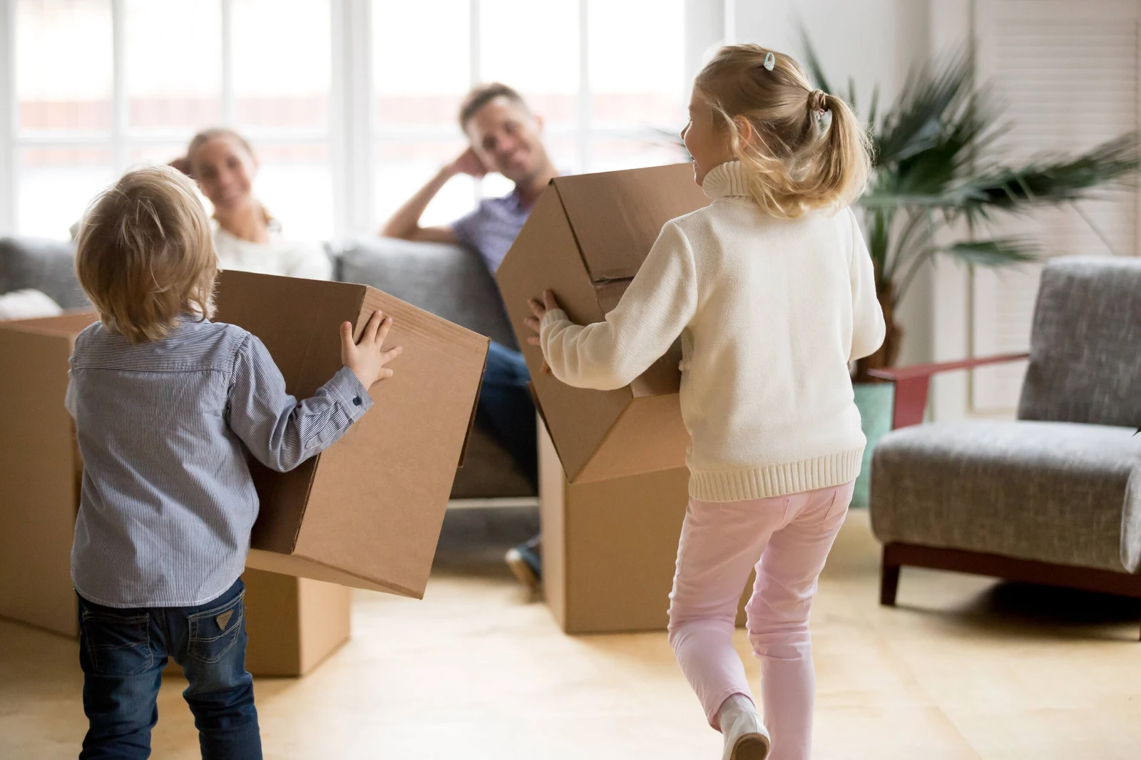 Rear view of children playing with boxes on moving day