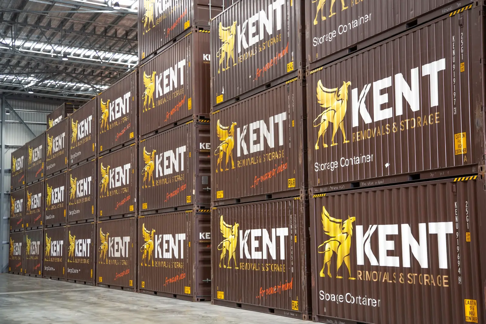 Stacked Kent Removals & Storage shipping containers inside a warehouse storage facility