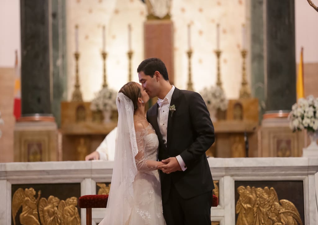 The bride and groom sharing a kiss at the alter 
