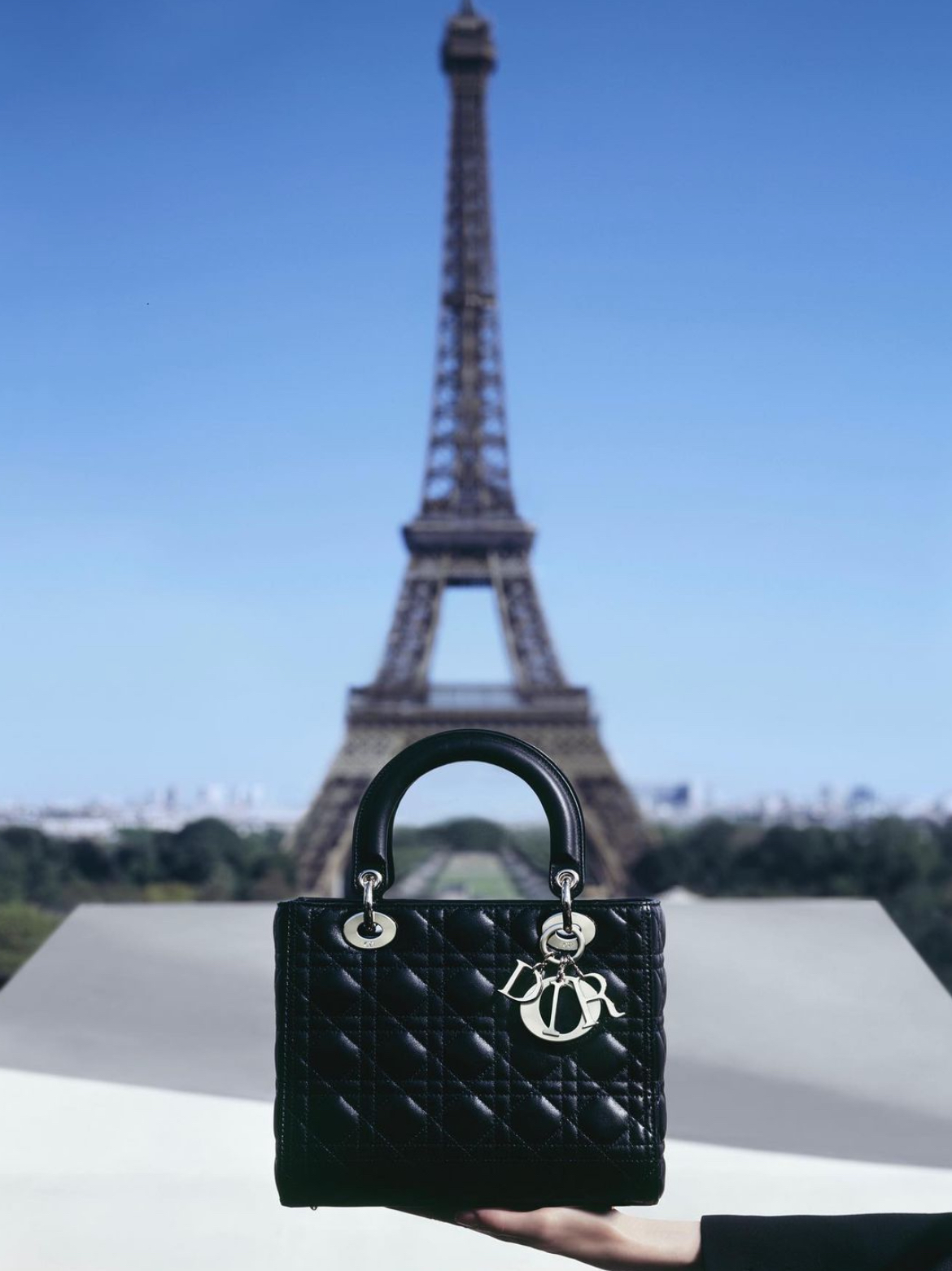 Photo of a Dior bag in front of the Eiffel Tower.
