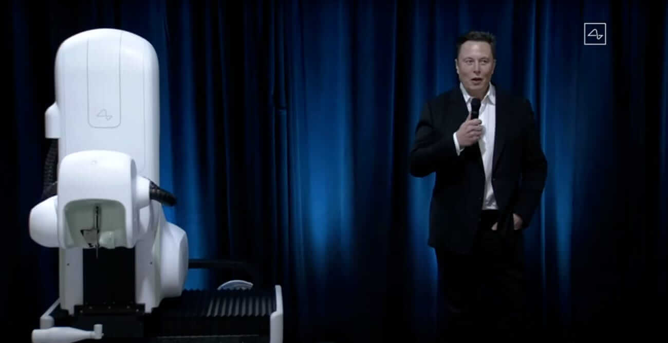 Elon Musk talking about Neuralink beside the robot.