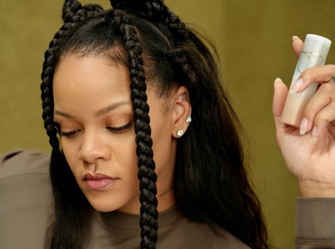 Rihanna holding a product from her brand Fenty Beauty.