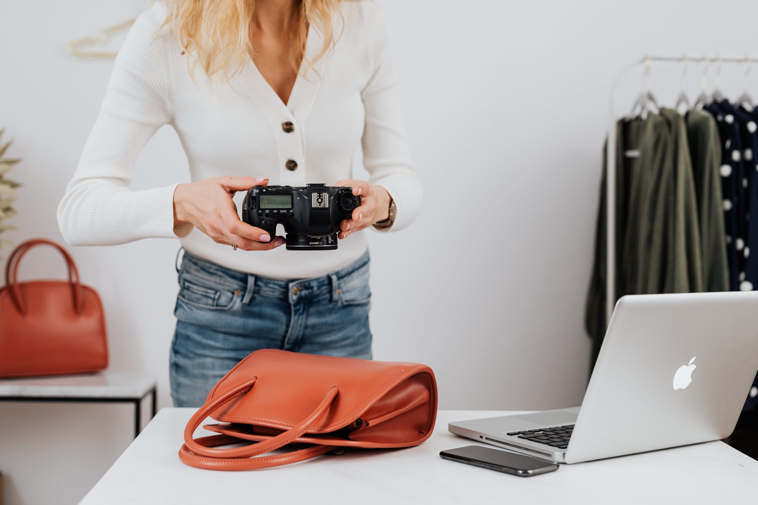 Woman holding a DSLR camera taking a picture of a handbag