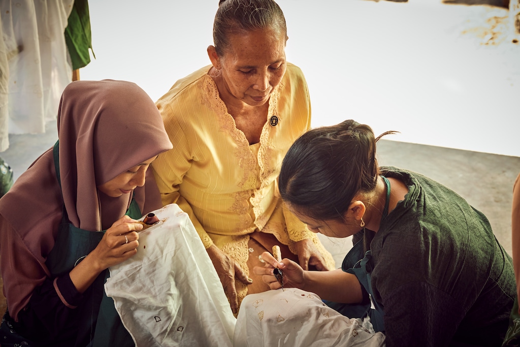 Batik artisan, Ibu Srikanthi supervises two younger women drawing patterns in one of SukkhaCitta’s craft schools located in Rumah SukkhaCitta, East Java. ©Rolex / Sébastien Agnetti