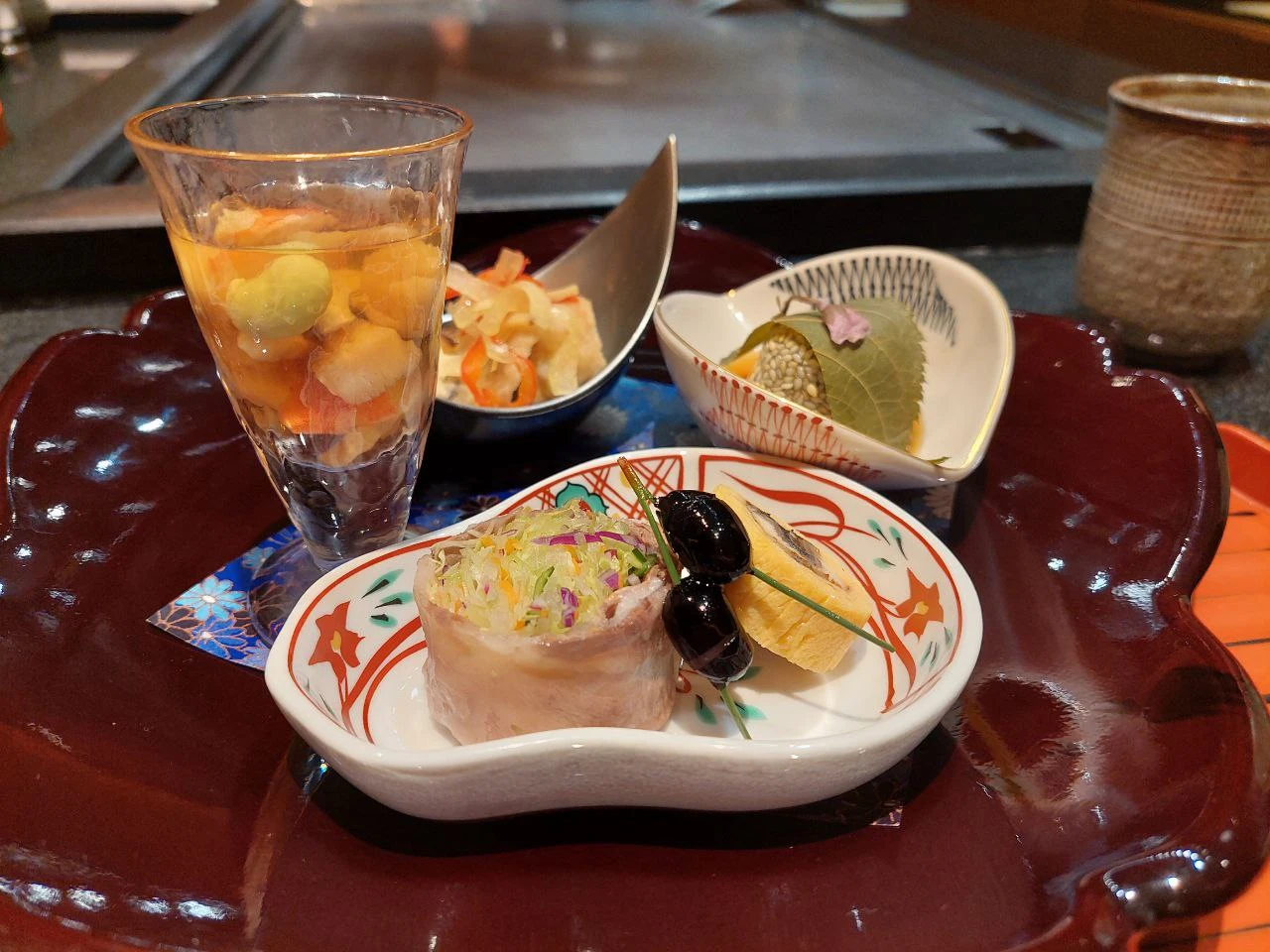Clockwise, from the left: A kaiseki of daiquiri jelly with vegetable and shrimp; nanban-style oyster; mugwort mochi; vegetables wrapped in wagyu and unagi in tamago 