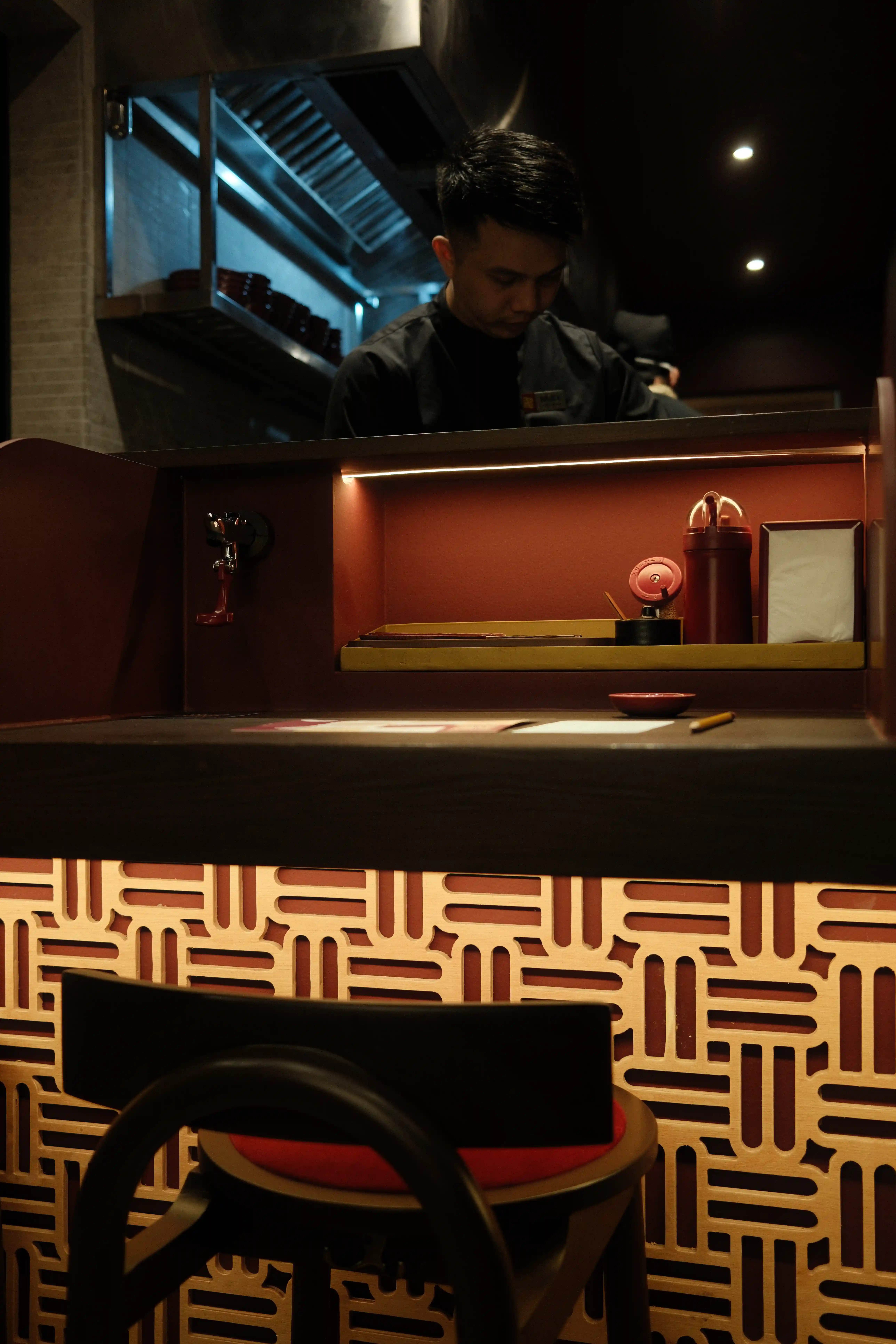 Bar seating at Mugen, complete with a water station, condiments, sauces, chopsticks, and napkins