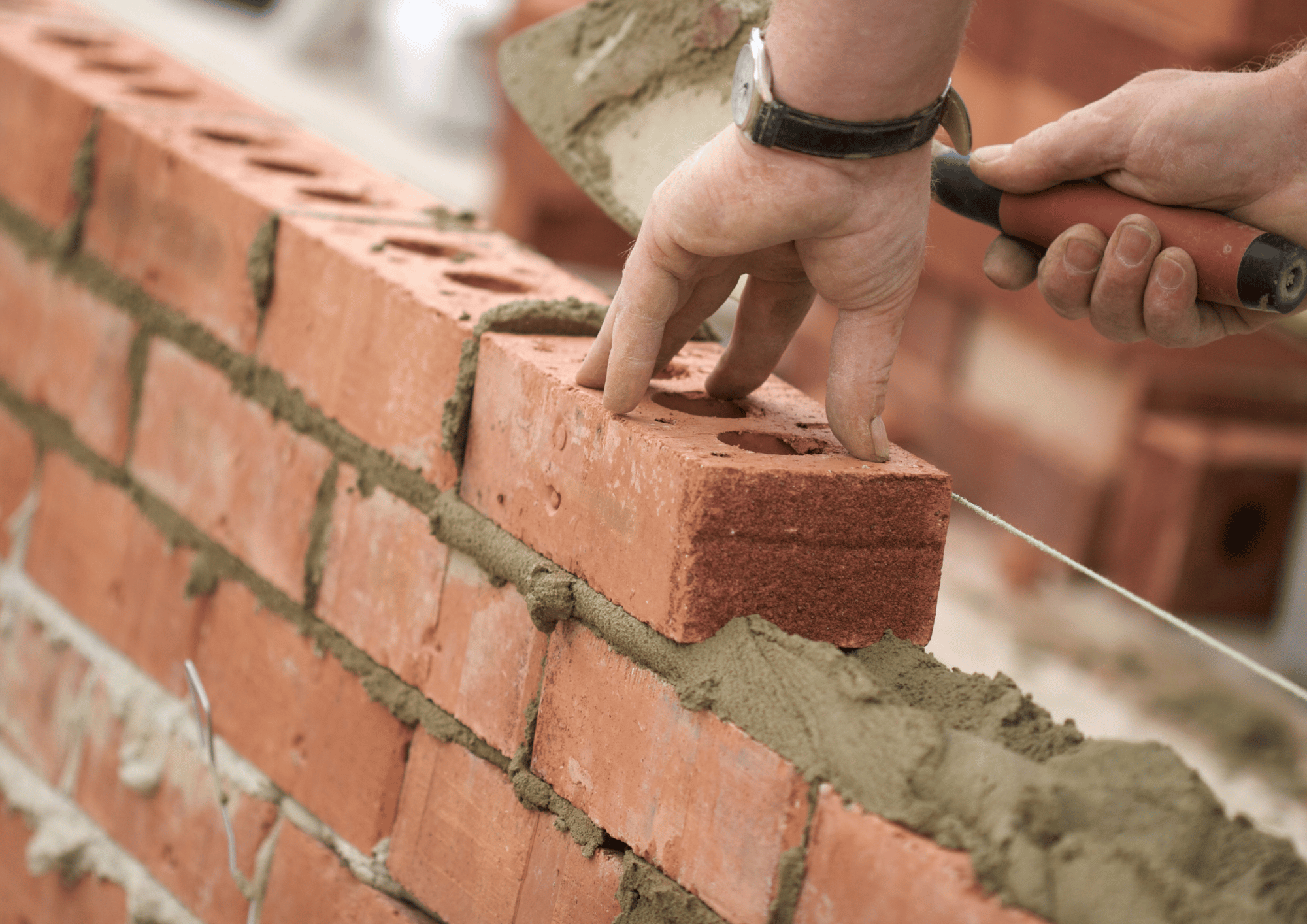 Hands laying bricks to build a house