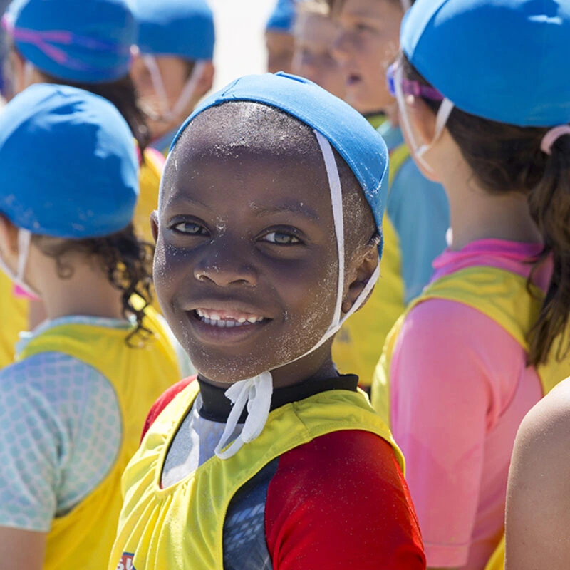 A child smiling in a swim cap at a multicultural beach program