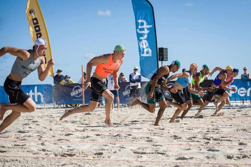 Competitors racing in a beach sprint at a surf life saving carnival