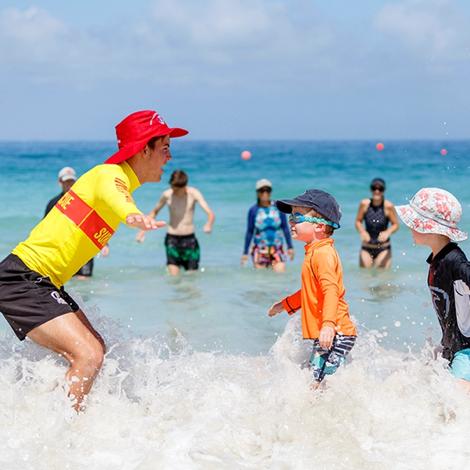 Children and parents taking part in a SurfBabies session in the shallows