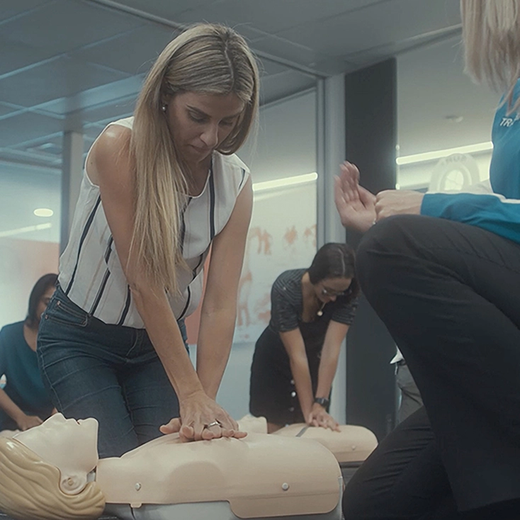 A trainer guiding a student through CPR on a manikin