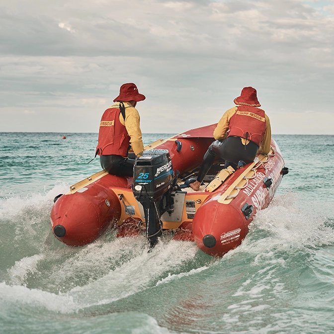 An inflatable rescue boat and crew powering through the surf