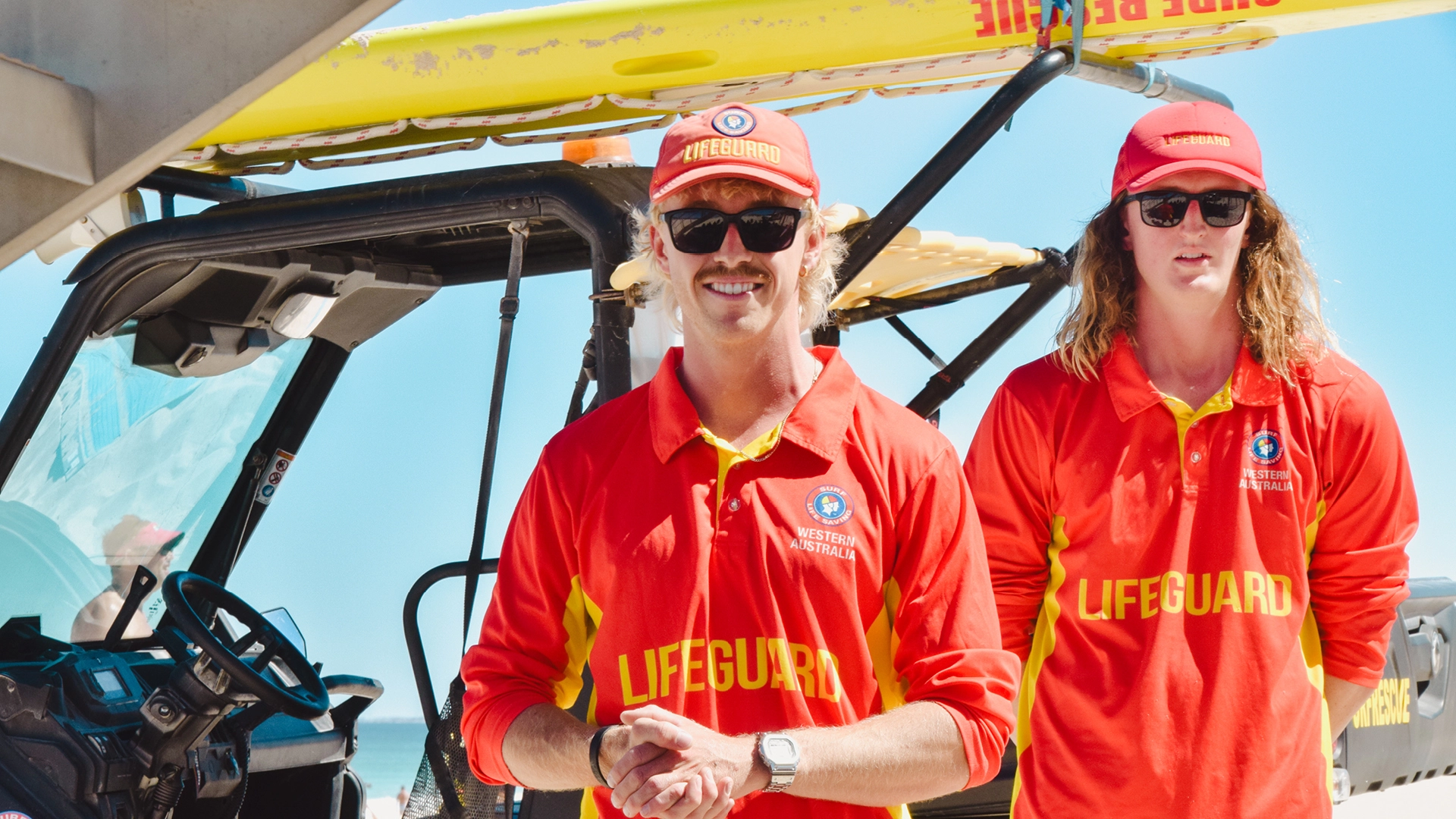 Two lifeguards beside a beach patrol vehicle