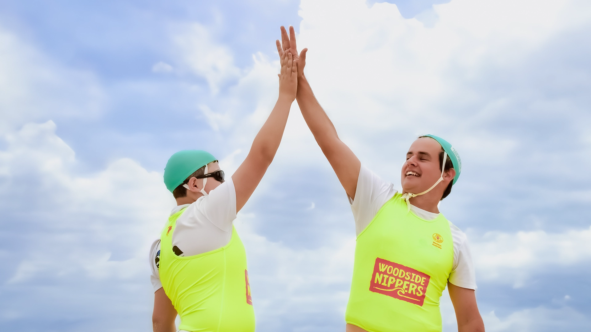 Two participants high-fiving at an all-abilities beach program