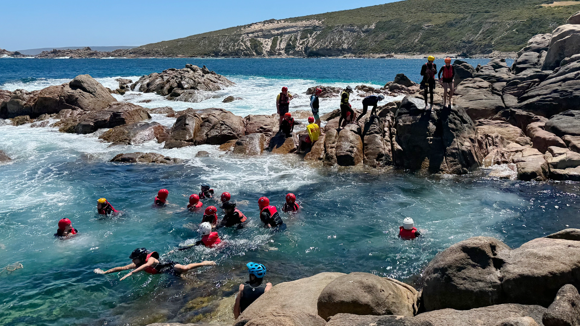 Youth camp participants swimming at a rocky bay