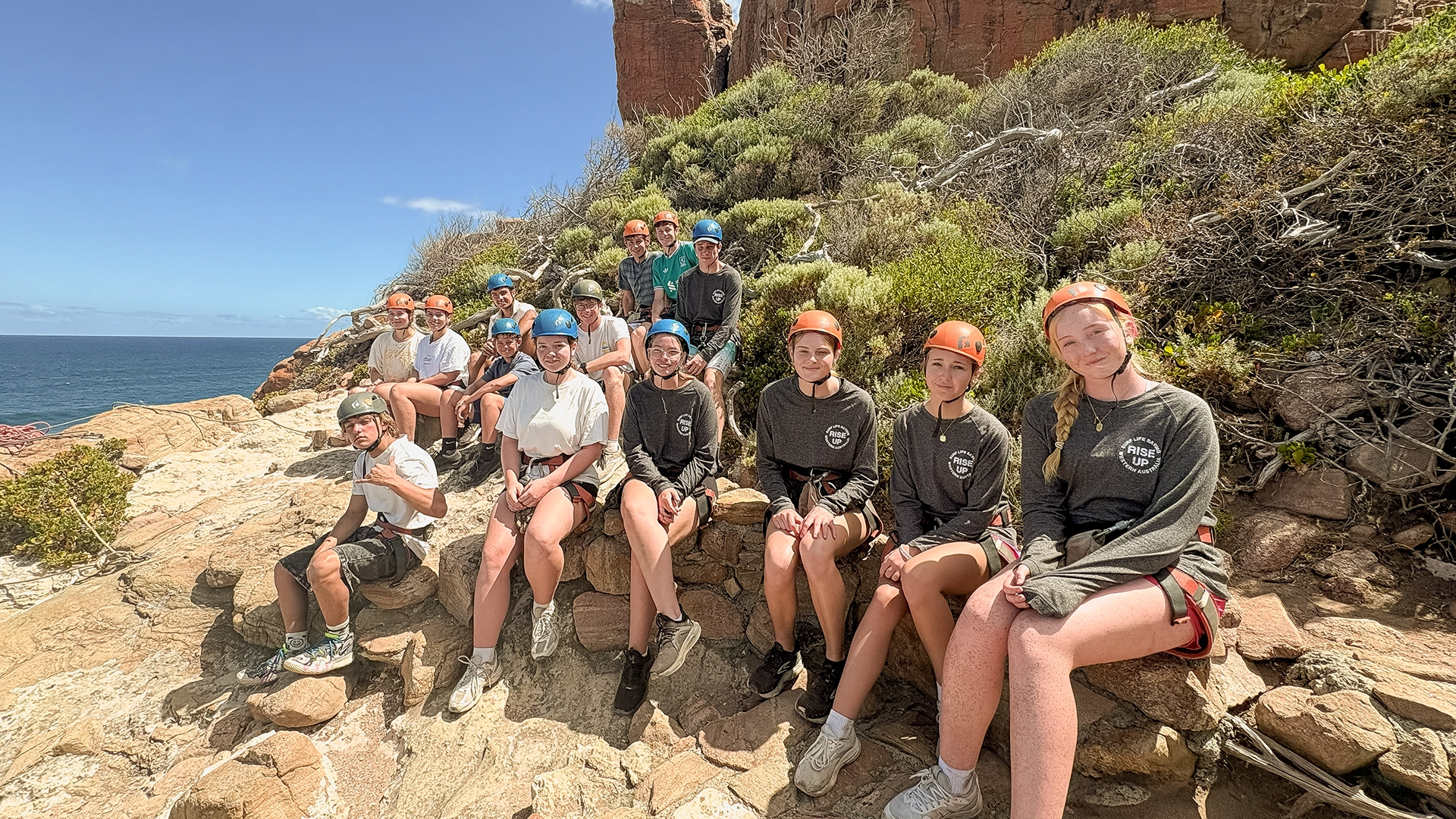Youth camp participants resting on a coastal walk