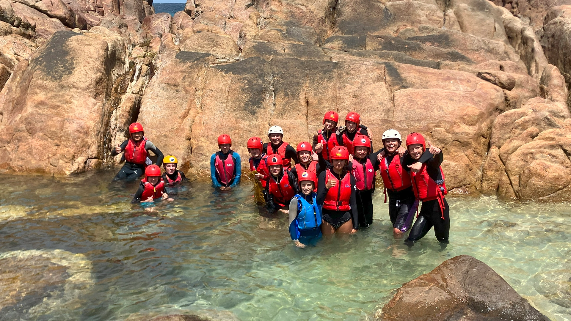 Youth camp participants exploring a coastal rock pool