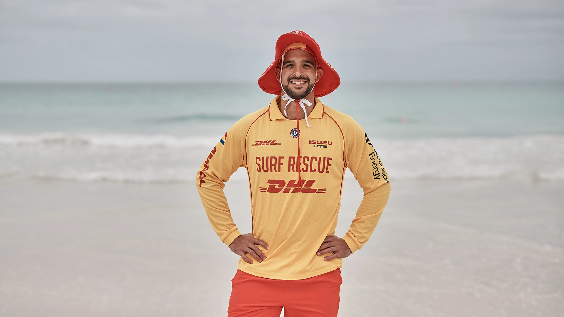 A surf lifesaver in a hooded patrol top on the beach