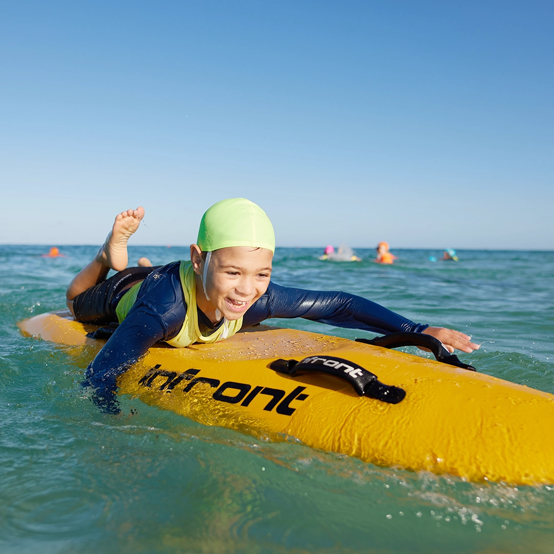A child paddling a nipper board in the shallows