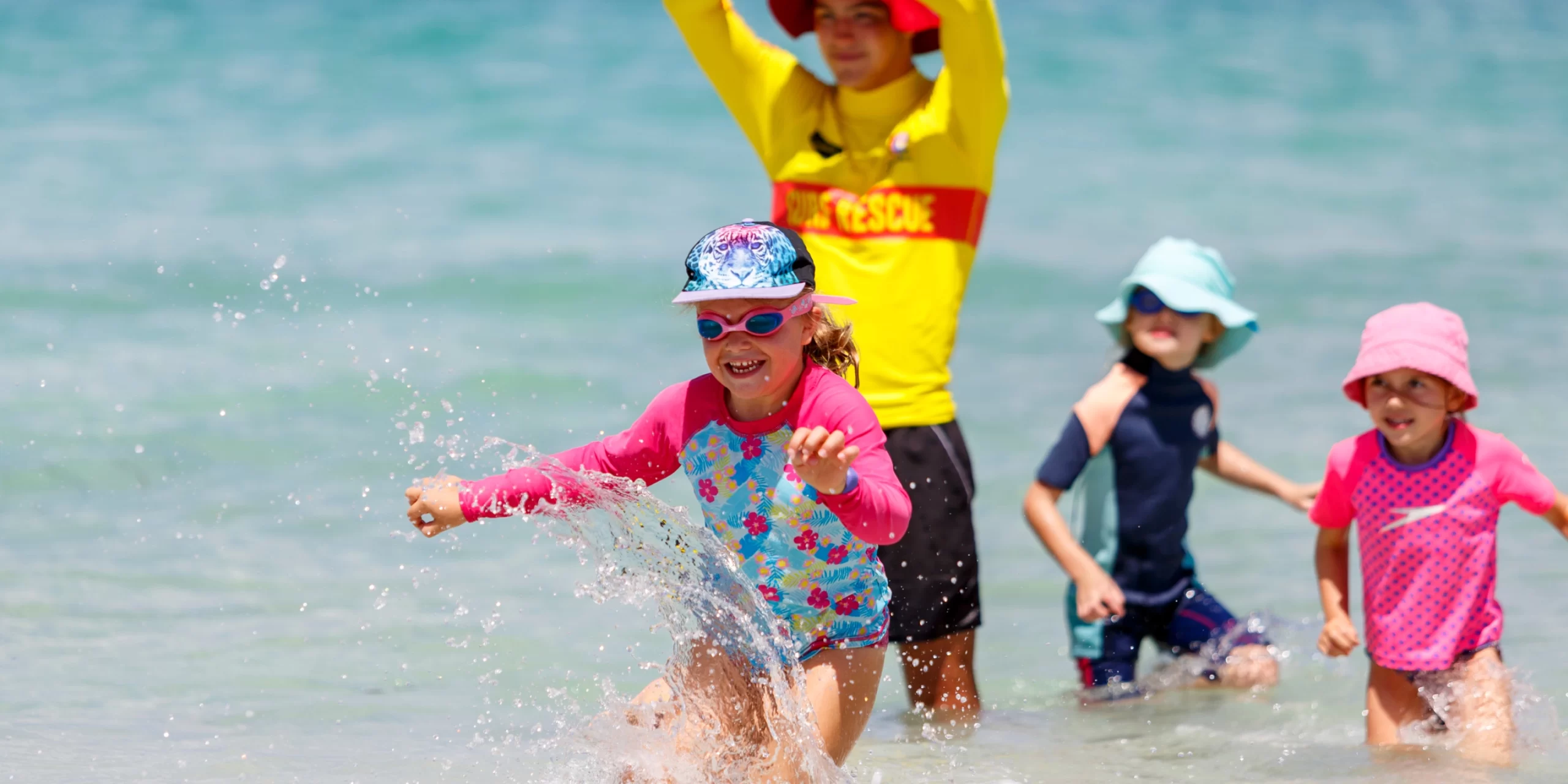 Children playing in the shallows with a surf lifesaver at a SurfBabies session