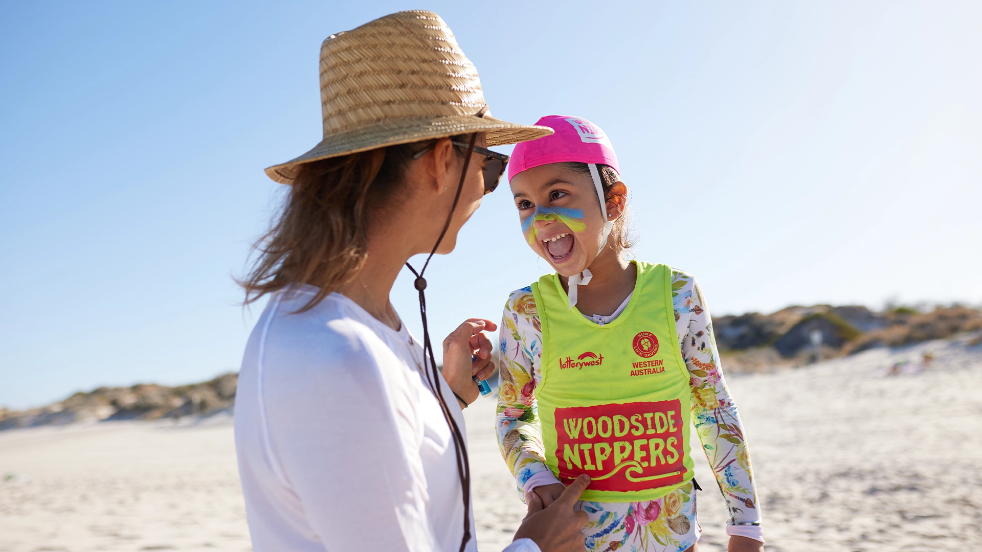 An adult applying zinc to a child wearing a Woodside Nippers vest