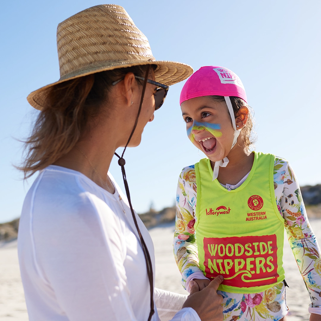 An adult and a Woodside Nipper wearing sun-safe hats at the beach