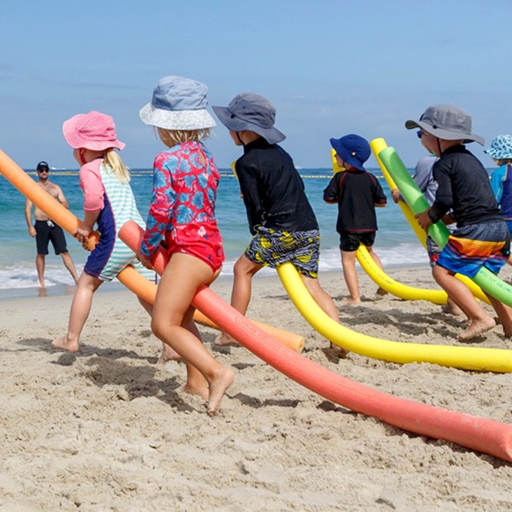 Children with pool noodles at a SurfBabies beach session