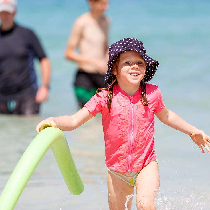 A young child in a sun hat at a SurfBabies session