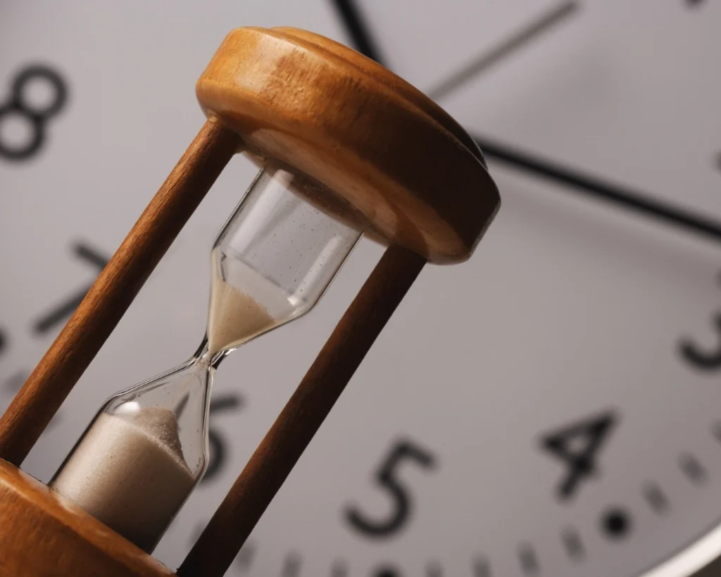 An hourglass in front of a clock