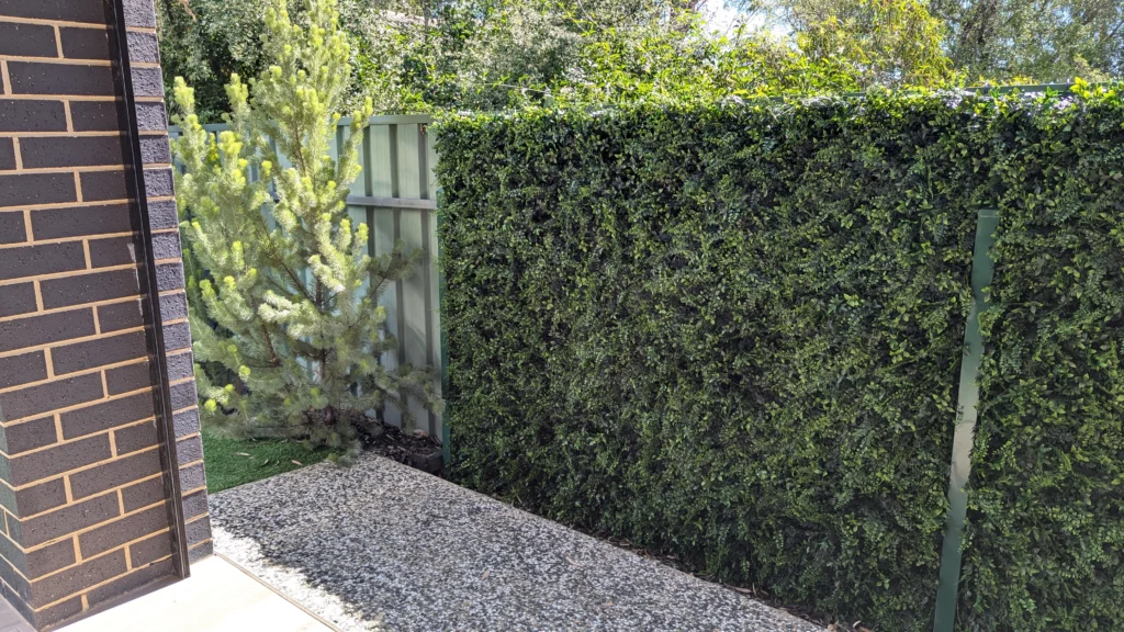 Artificial green wall panel installed on a fence