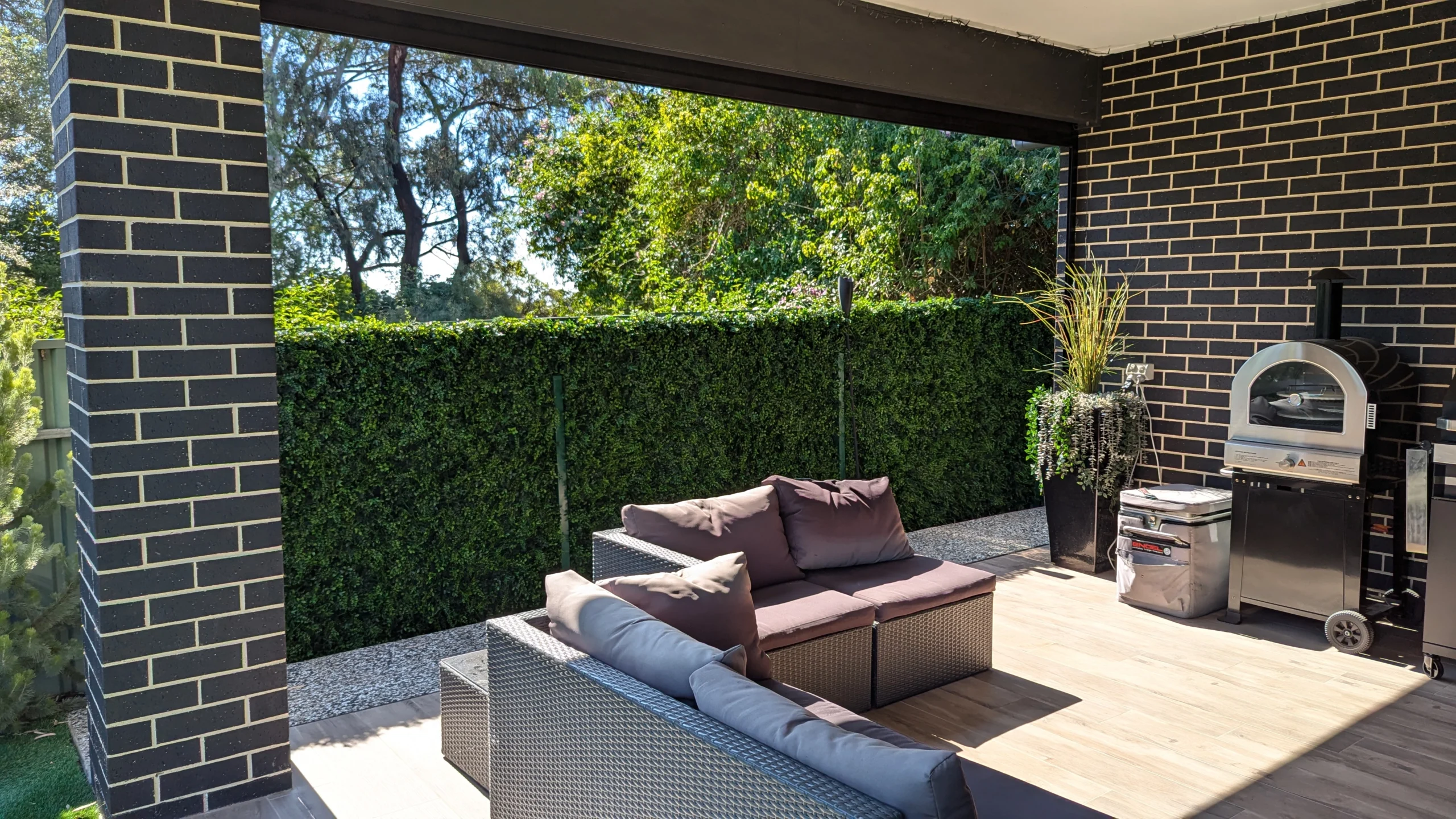 Artificial green wall attached to fence, viewed from a backyard patio