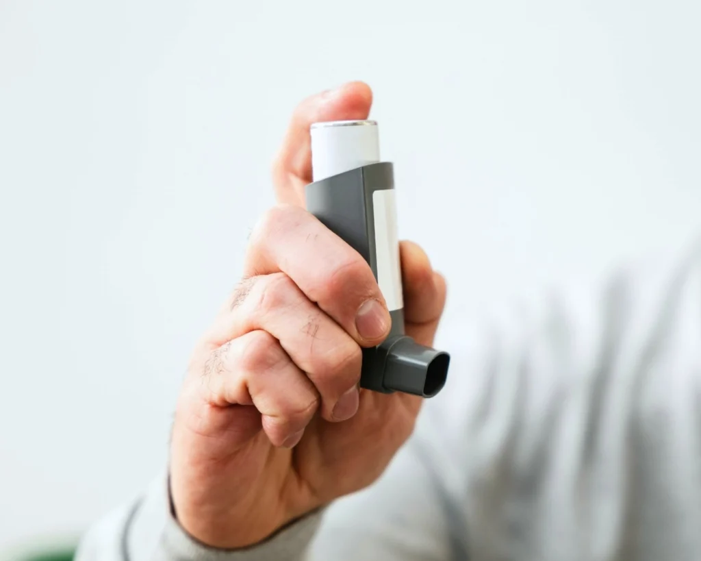 A man’s hand holding an asthma puffer