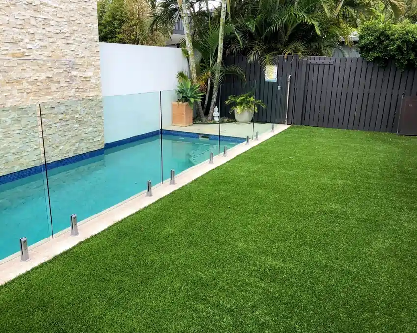 Artificial grass installed in a backyard alongside a swimming pool