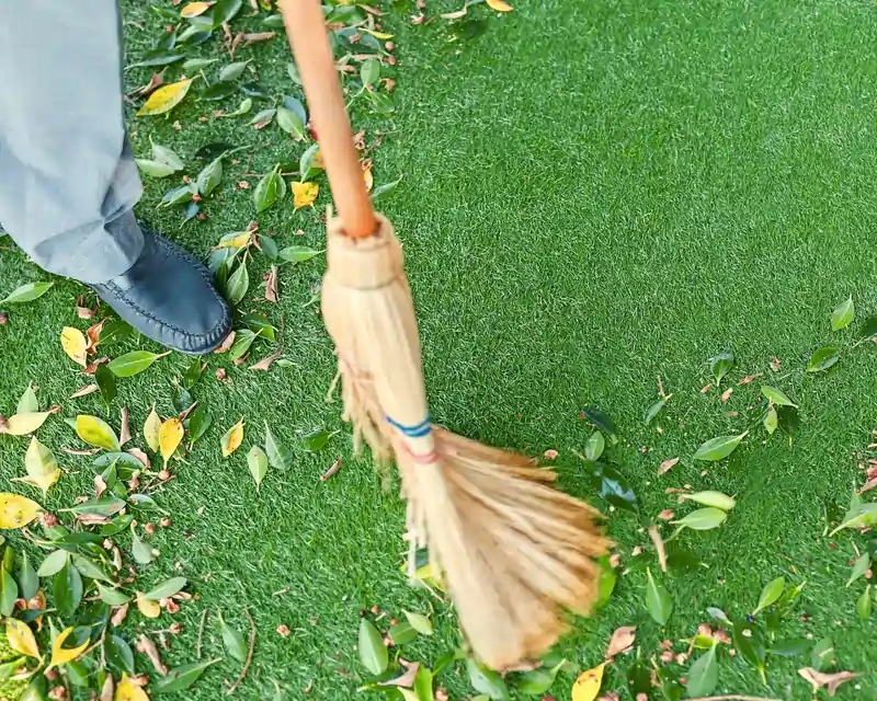 Homeowner sweeping up leaves on artificial grass