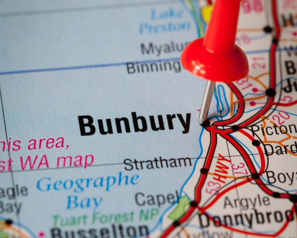 A paper map with a push pin placed on Bunbury, Western Australia.